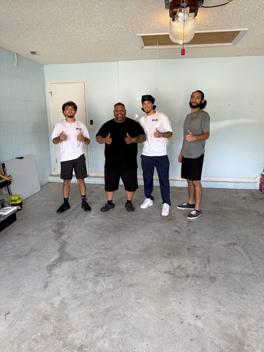 The Prime Junk Removals crew standing with a customer in his emptied, swept garage after the job